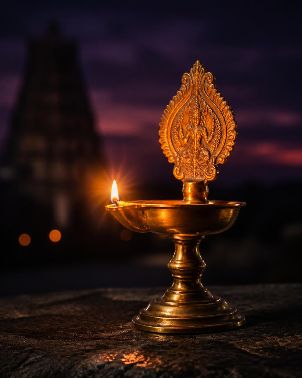 Lit brass diya glowing in the dark